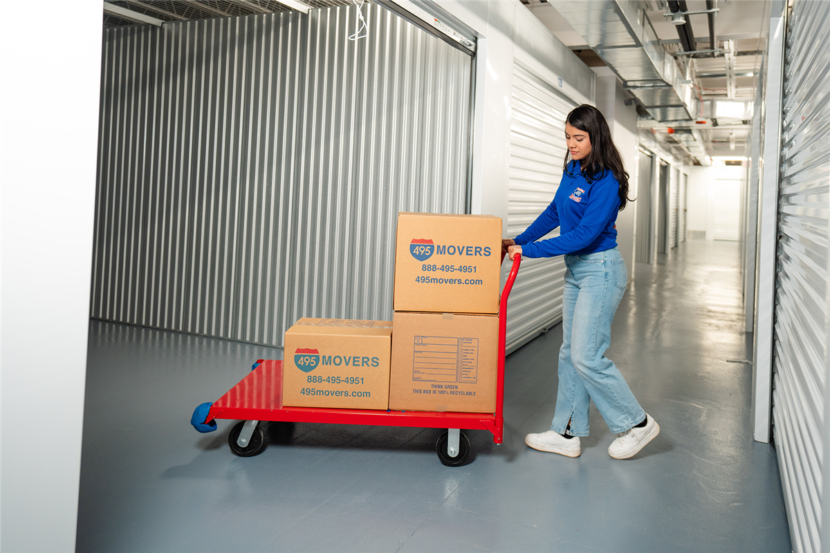 495 Movers employee pushing moving boxes into a storage unit